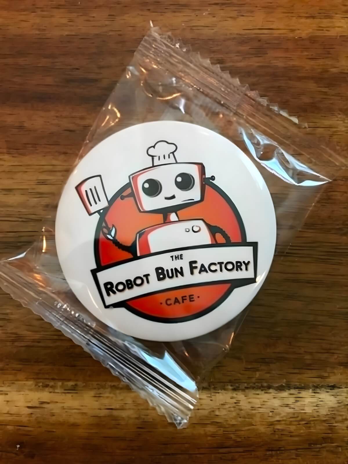 The Robot Bun Factory Cafe logo badge on a wooden table