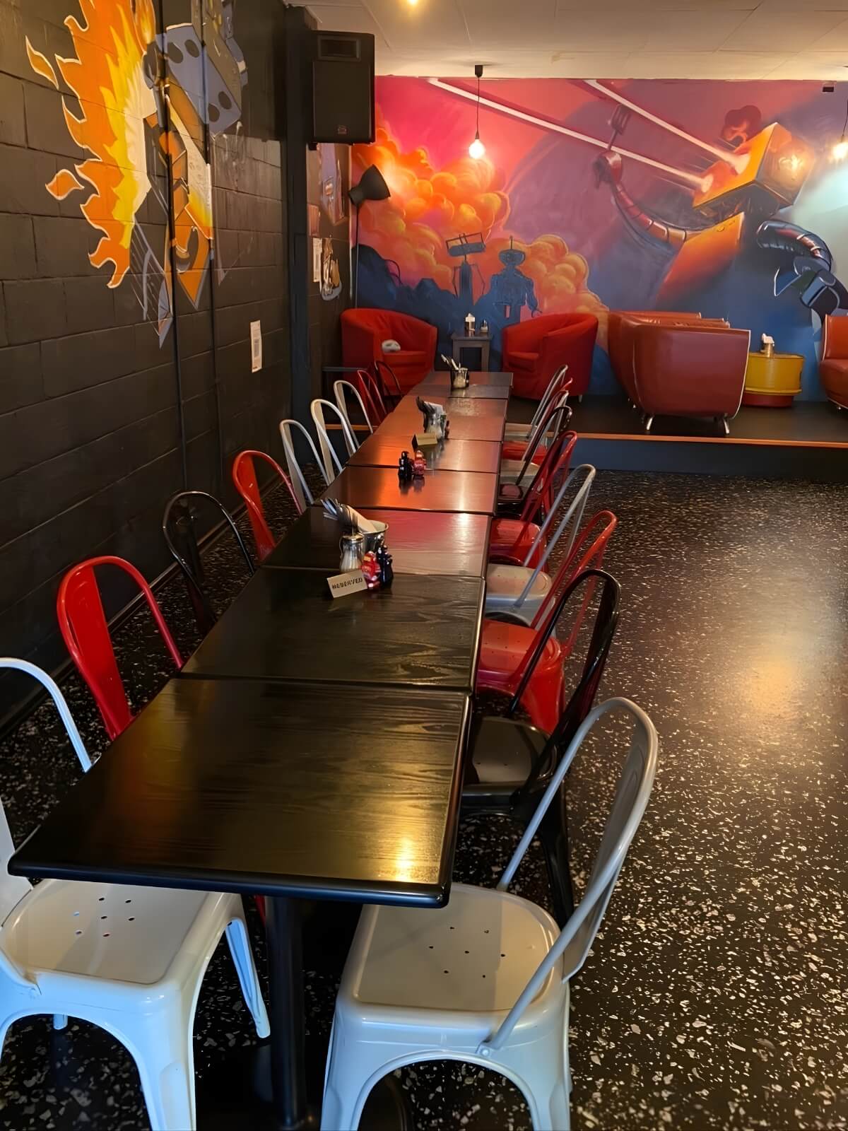 Robot Bun Factory cafe seating area with long tables, red chairs and robot wall mural