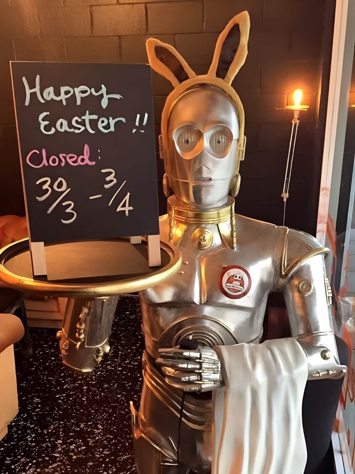 Silver robot holding a Happy Easter sign inside The Robot Bun Factory Cafe